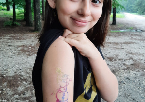 Dziewczynka pokazująca na ramieniu tatuaż bałwanka